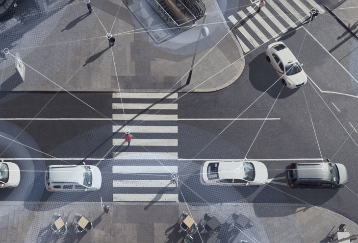 Photo aérienne d'une scène de rue avec des voitures conduisant et des personnes marchant, avec des lignes superposées pour montrer la connectivité du Wi-Fi et du LTE.